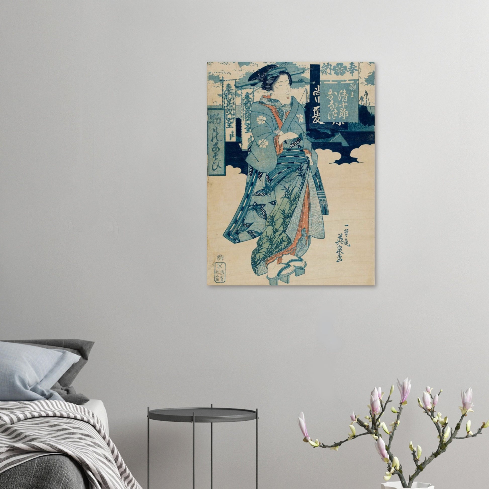 Traditional Japanese artwork on a wall above a bed with a side table and decorative branch.