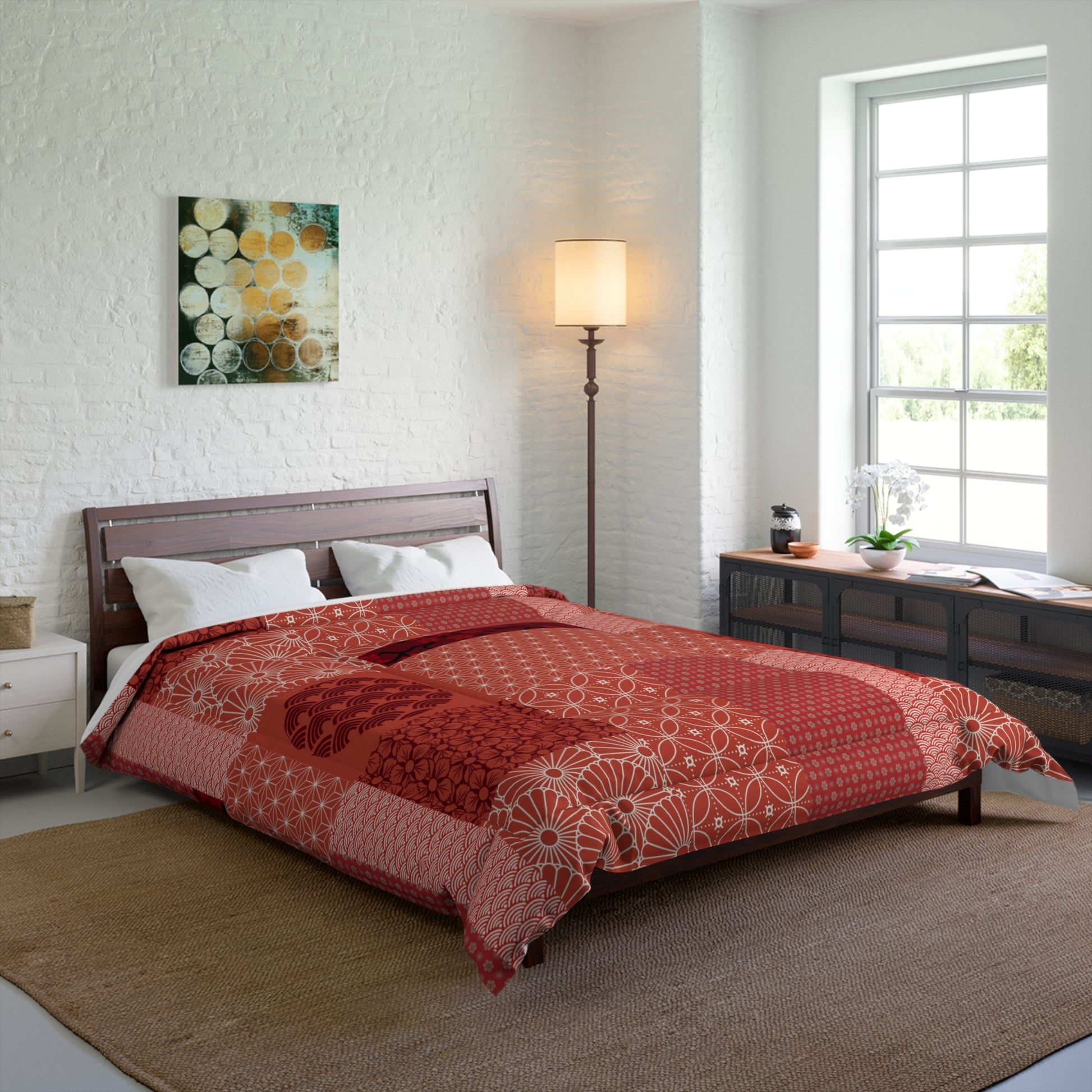 Bedroom with a bed covered in a red and white patterned comforter, a lamp, and a painting on the wall.