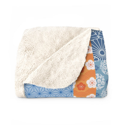 Folded blanket with white sherpa interior and colorful geometric pattern exterior on a white background