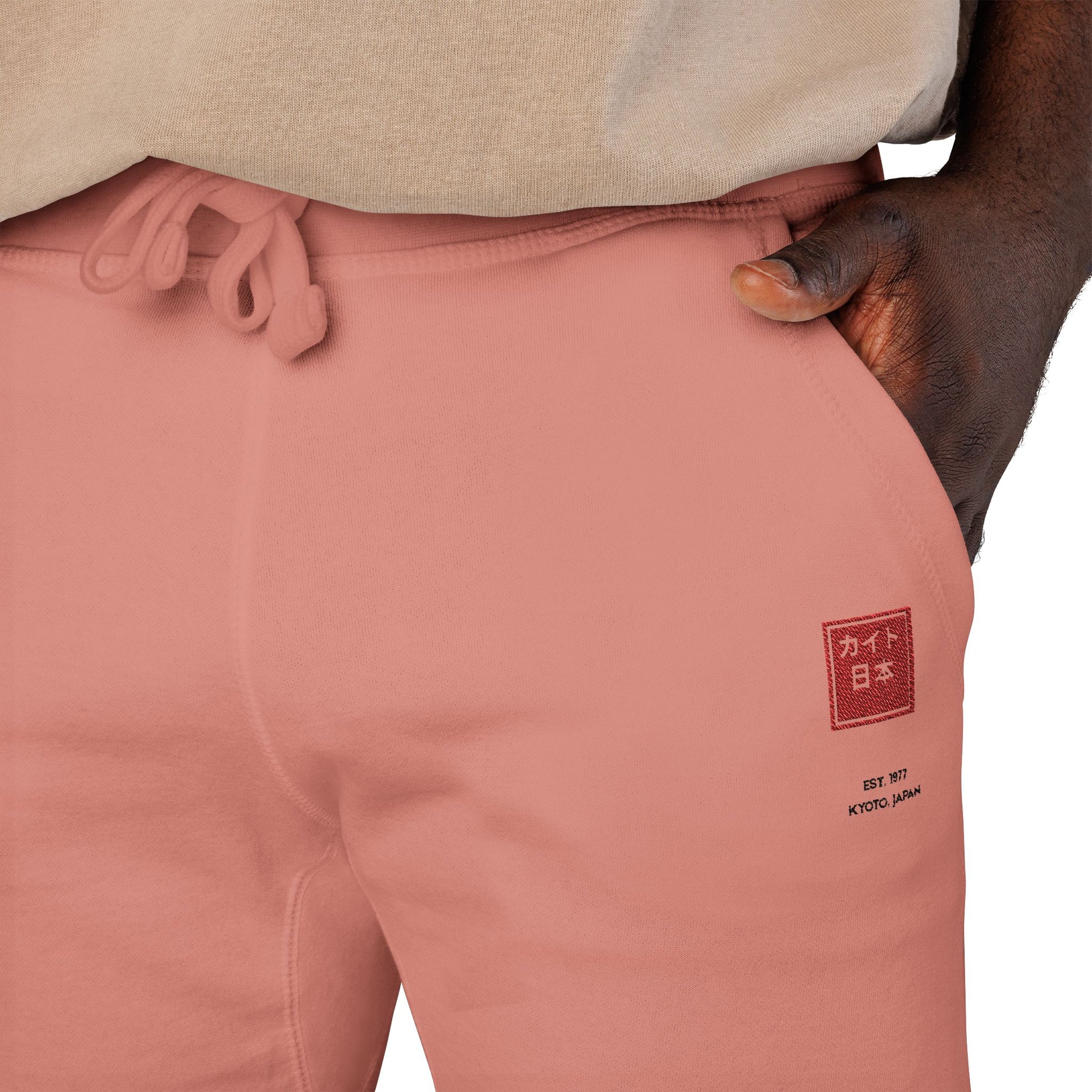 Close-up of pink sweatpants with a logo on the leg, worn by a person.