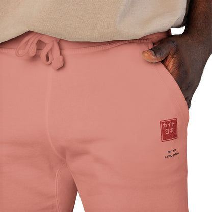 Close-up of pink sweatpants with a logo on the leg, worn by a person.