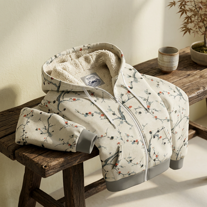 KAITO Japan Design winter zip-up hoodie featuring a plush cream sherpa lining, mineral-grey ribbed trim, and a textured off-white exterior printed with a delicate winter sakura cherry blossom pattern.