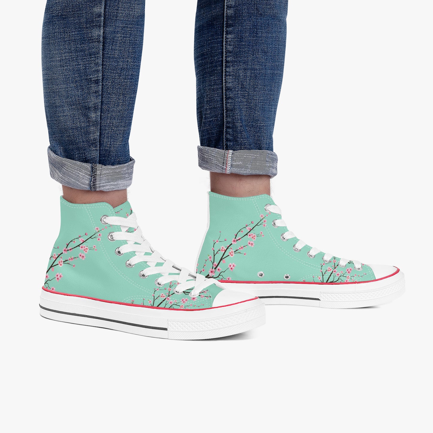 Mint green high-top sneakers with floral design worn with rolled-up jeans on a white background