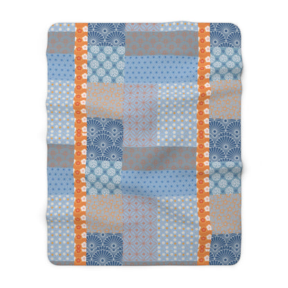 Patchwork blanket with blue, orange, and gray patterns on a white background