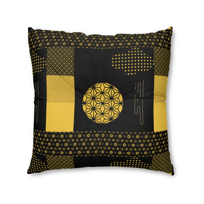 A square decorative throw pillow featuring a black and mustard yellow geometric patchwork design with a central flower-of-life motif, shown on a plain white background.
