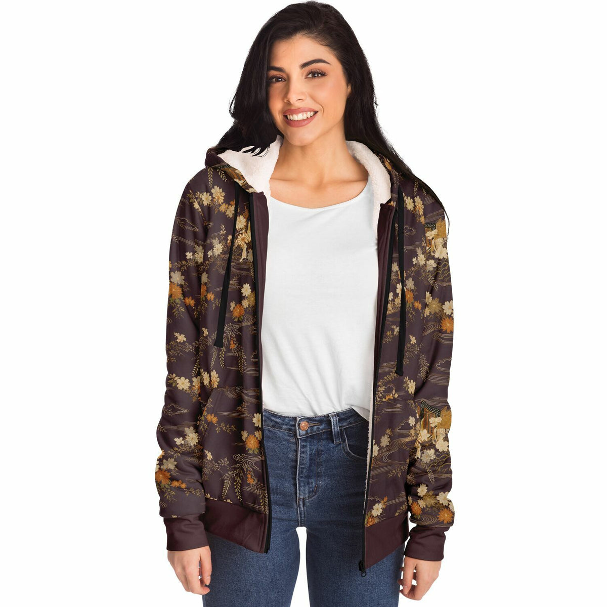 A woman modeling a brown hooded zip-up jacket with an all-over floral pattern in muted gold, beige, and olive tones, worn over a white t-shirt and blue jeans against a plain white background.