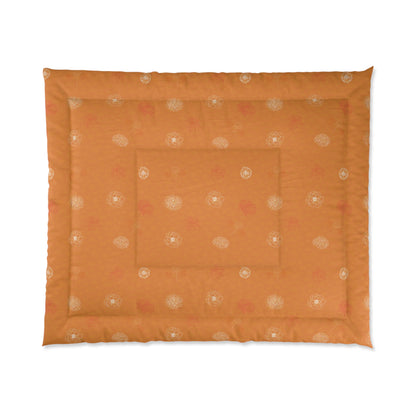 An orange quilted pet bed with a subtle pattern of small white and pink floral motifs, shown flat against a white background.