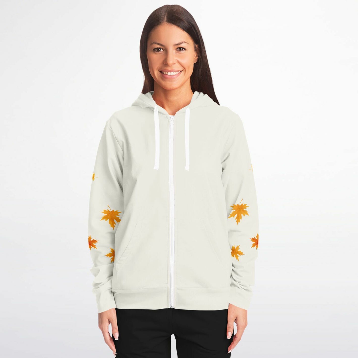 A woman modeling a light sage green zip-up hoodie with white drawstrings and orange maple leaf prints on the sleeves, set against a plain white studio background.