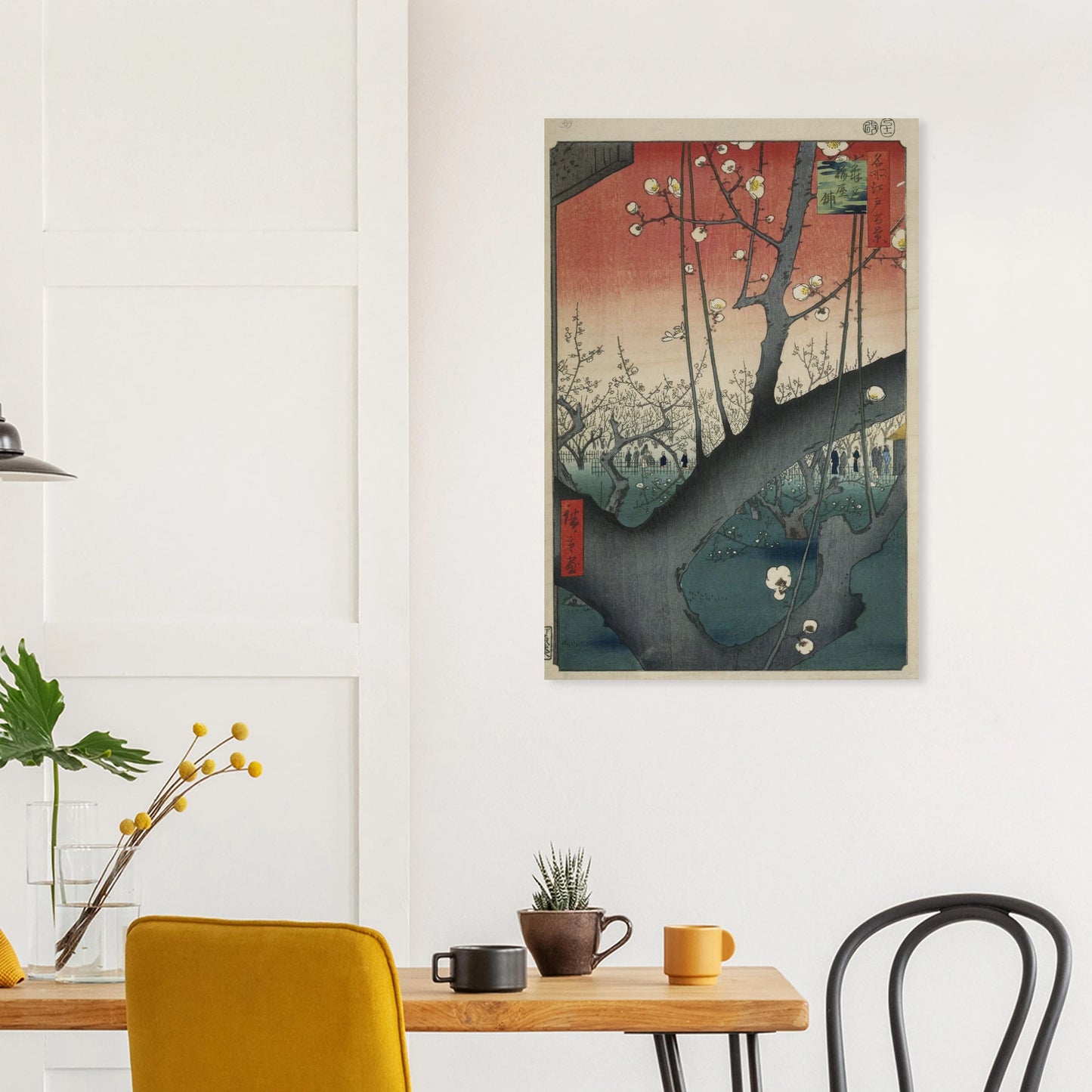 Framed artwork on a wall above a wooden table with chairs.