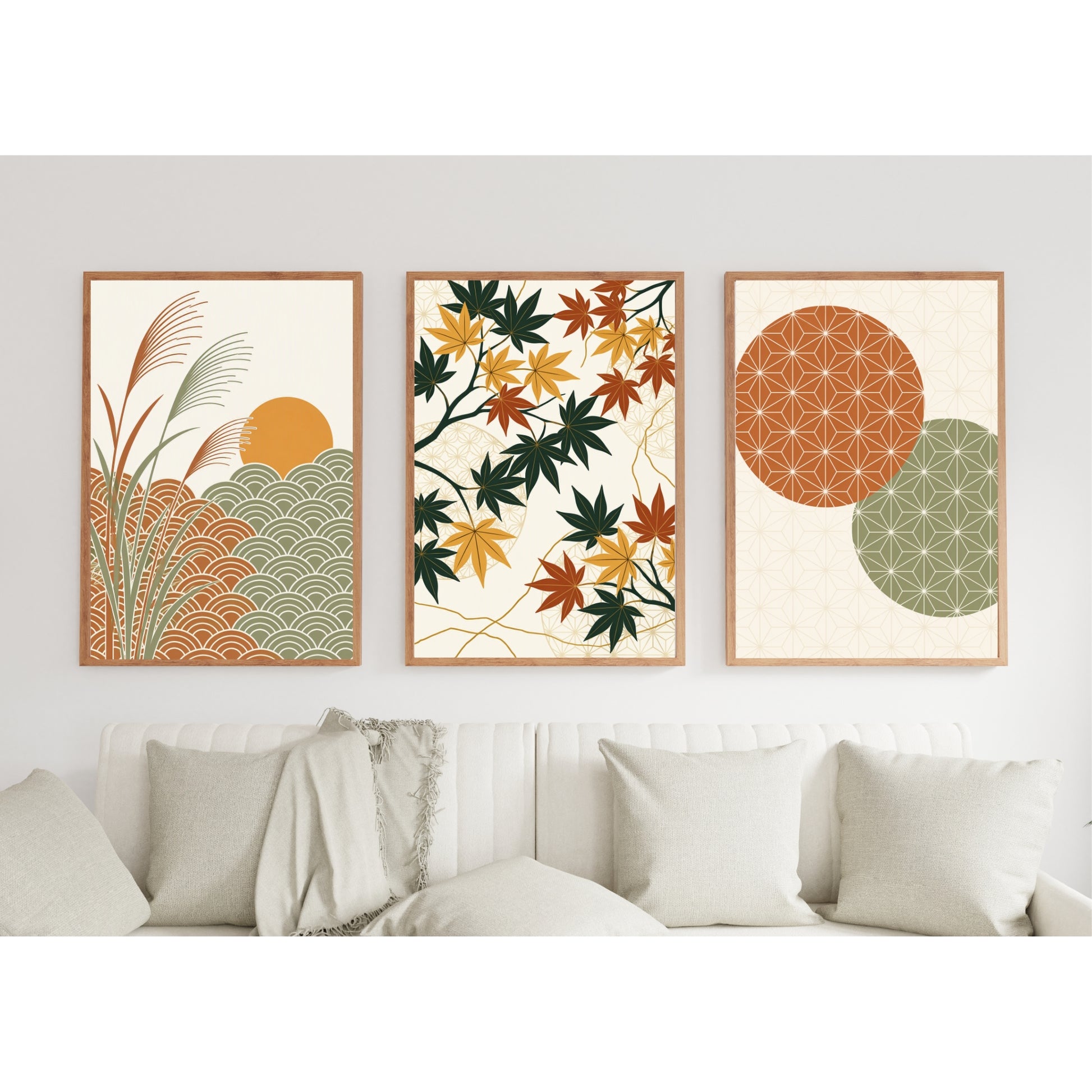 Three framed abstract and botanical wall art prints hang above a white sofa with neutral throw pillows in a bright, modern living room. The left print shows a sun over stylized grass and wave patterns in orange, green, and beige.