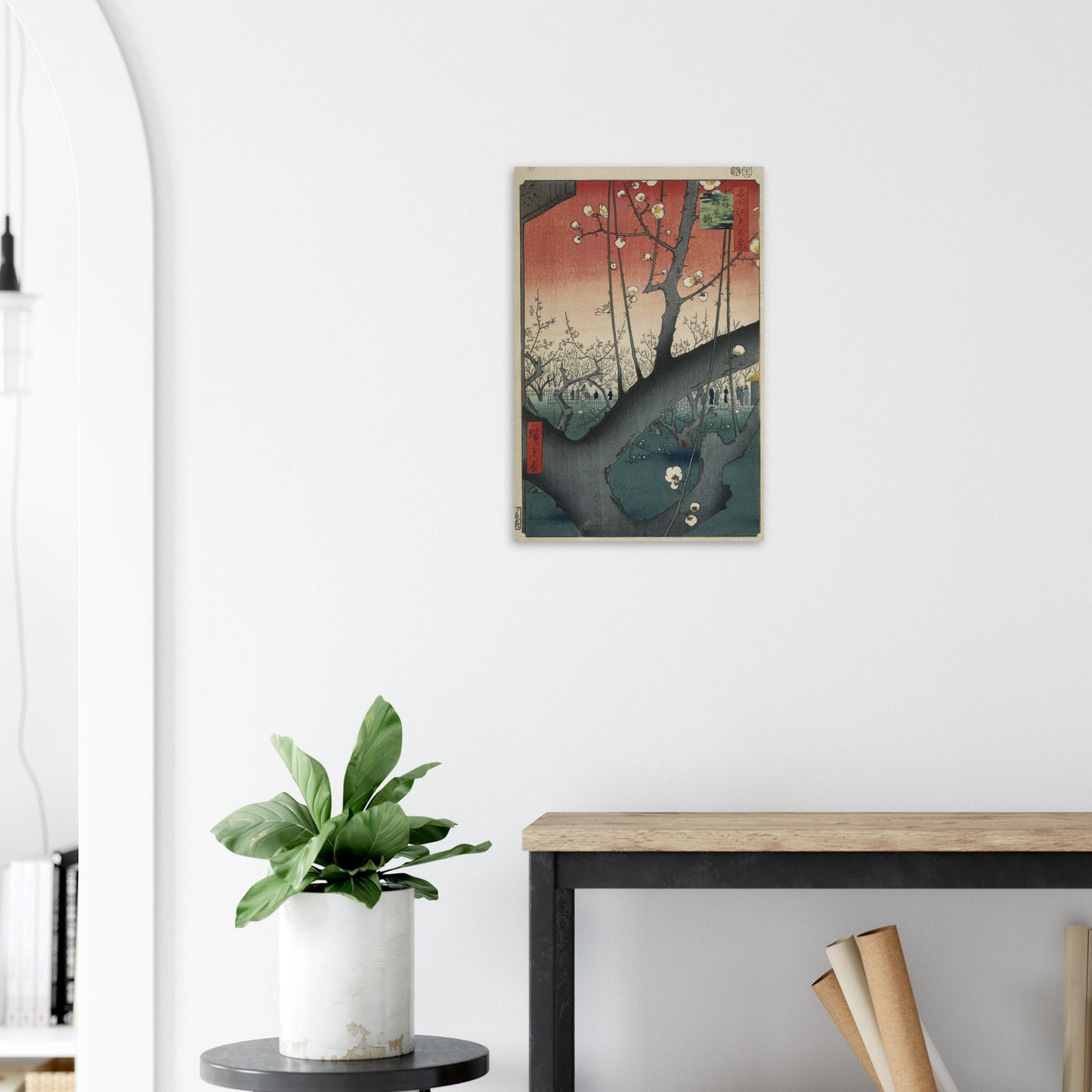 Poster of a city street scene on a white wall above a plant and desk.