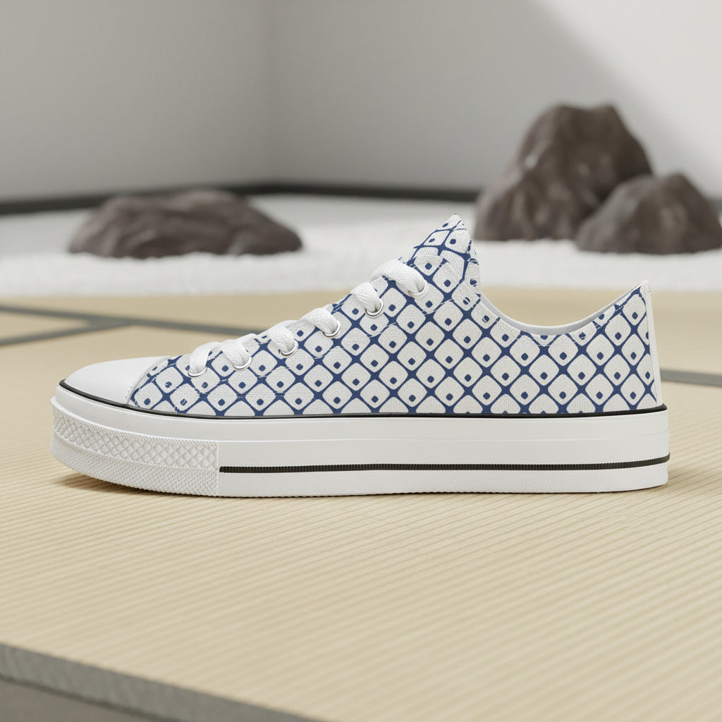 A side profile of a white low-top sneaker featuring a blue geometric diamond pattern inspired by traditional Japanese Shibori tie-dye techniques.