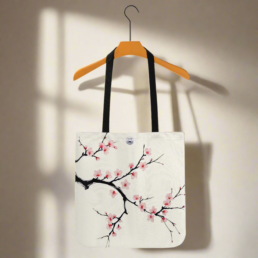 Tote bag with cherry blossom design on a hanger against a white background