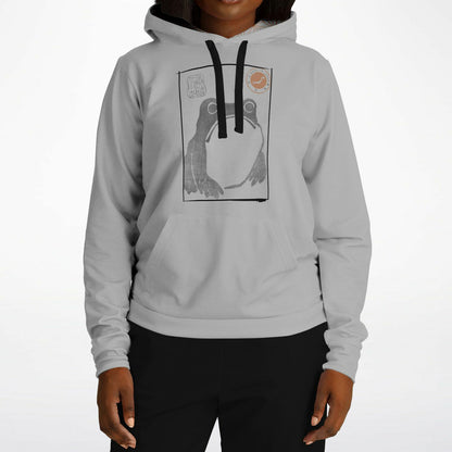 A person wearing a light gray pullover hoodie with a black drawstring and a large graphic print of a frog on the chest, paired with black pants, against a plain white studio background.