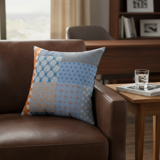 Decorative pillow on a brown leather couch with a side table and glass of water in the background.