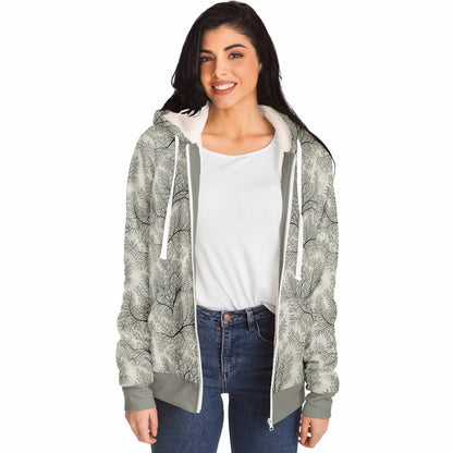 A woman modeling a light gray and white patterned zip-up hoodie with a white sherpa-lined hood, worn over a white t-shirt and blue jeans against a plain white background.