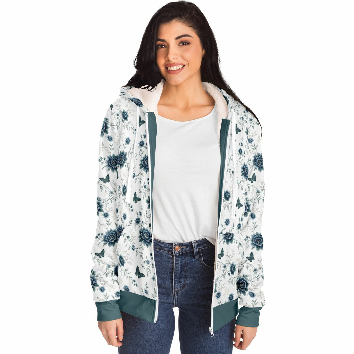 A woman modeling a white zip-up hoodie with a blue floral print, dark green trim, and a white hood, worn over a white t-shirt and blue jeans against a plain white background.