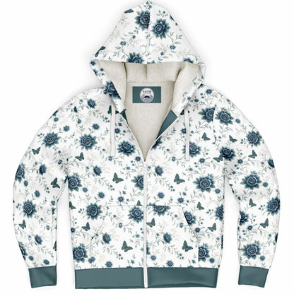 A white zip-up hoodie with a blue floral and butterfly pattern, featuring a cream-colored fleece lining and solid blue-green cuffs and hem.