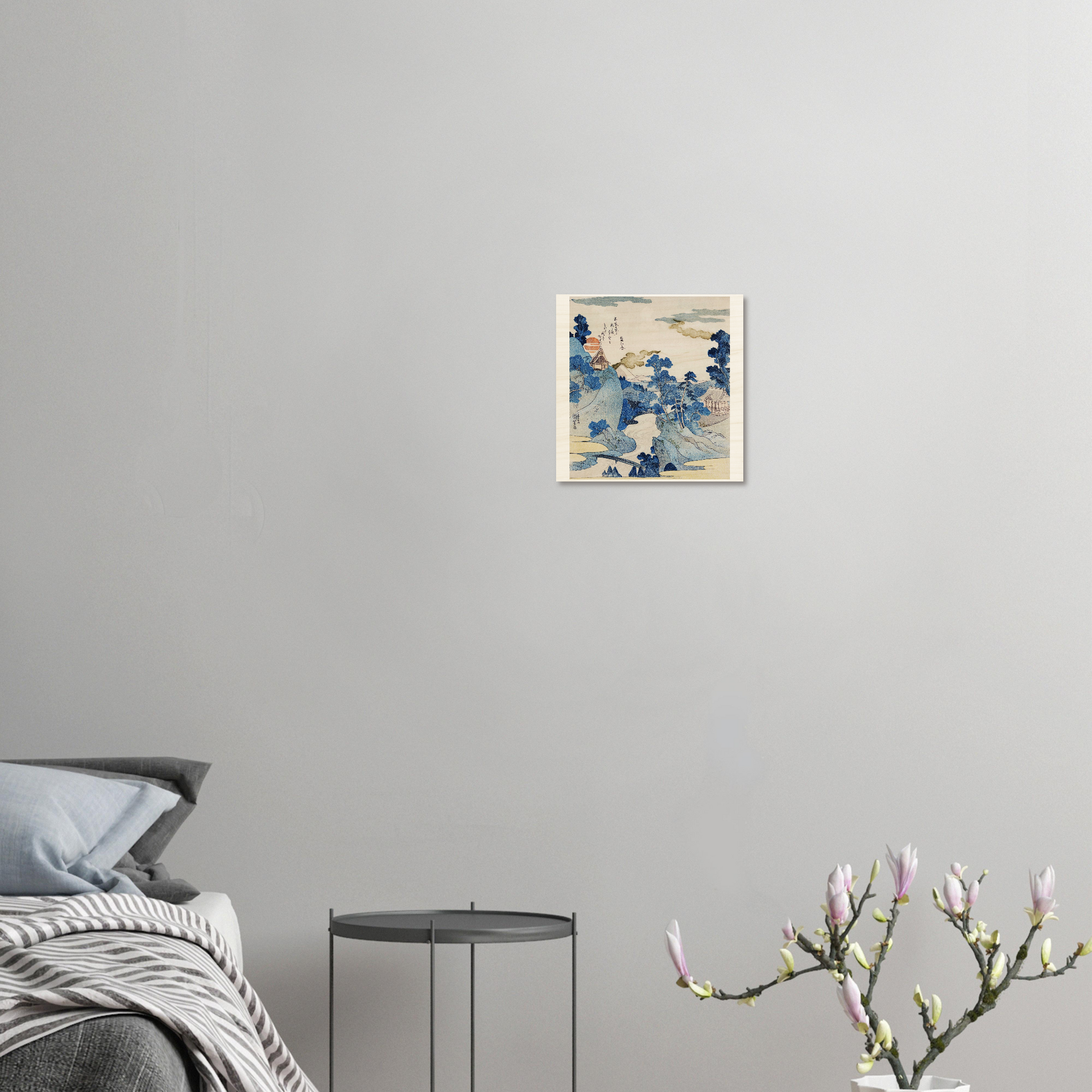 Framed artwork on a gray wall above a bed with a side table and decorative branch.