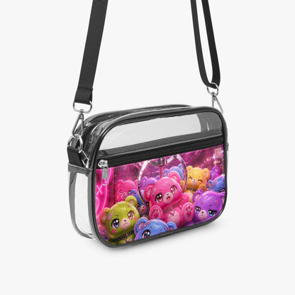 A clear plastic crossbody bag with a black strap and trim, featuring a colorful printed graphic of cute cartoon teddy bears on the front pocket, set against a light gray background.
