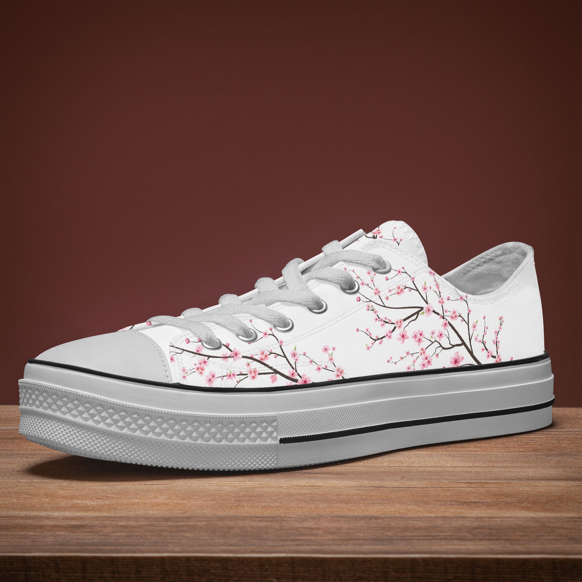 White sneaker with cherry blossom design on a wooden surface and brown background