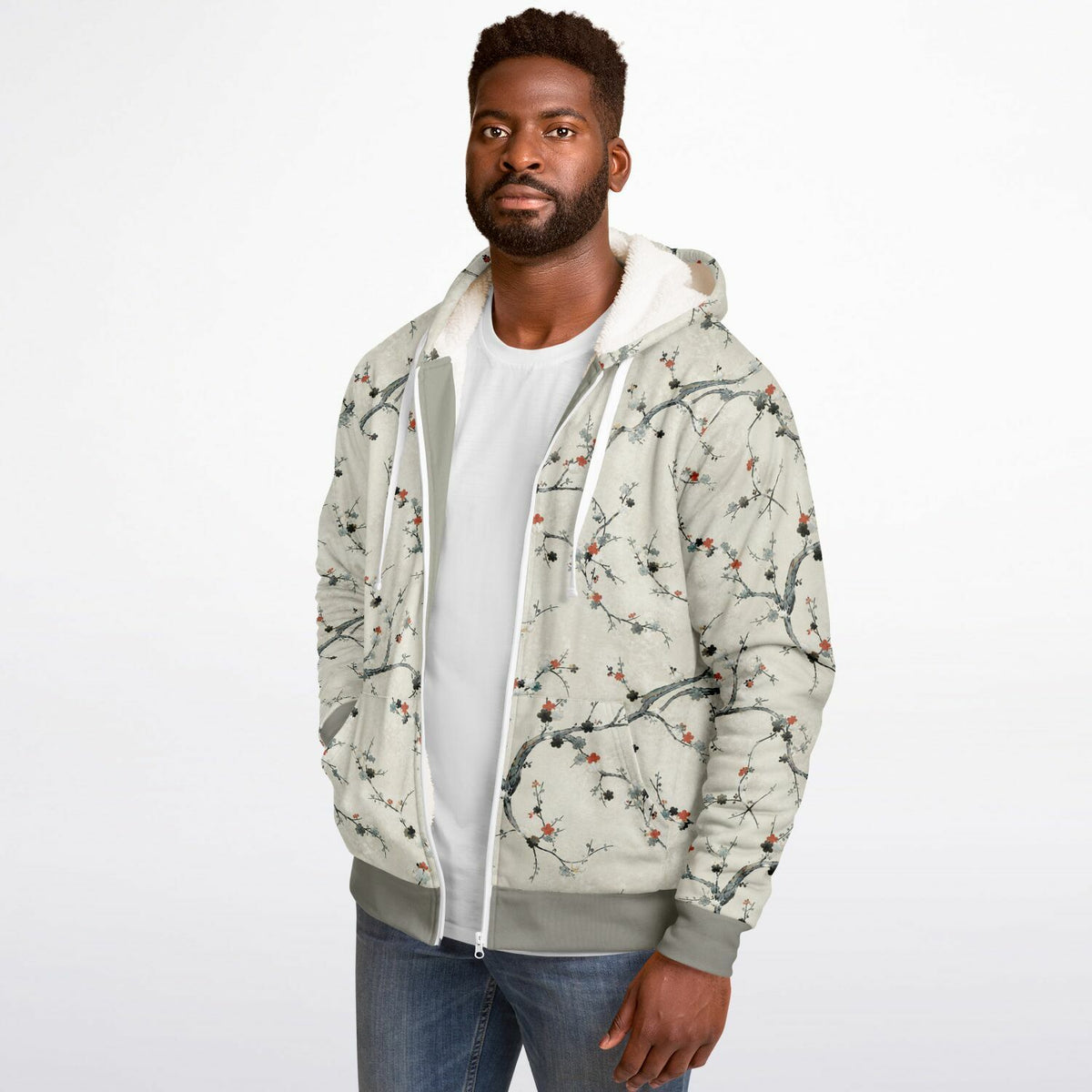 A man wearing a light beige hooded jacket with a gray and red cherry blossom branch pattern, layered over a white t-shirt and blue jeans, against a plain white background.