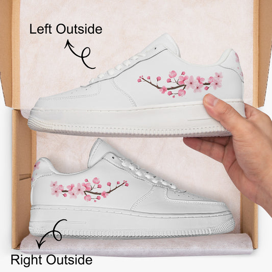 White sneakers with pink floral design held by a hand, showing left and right sides.
