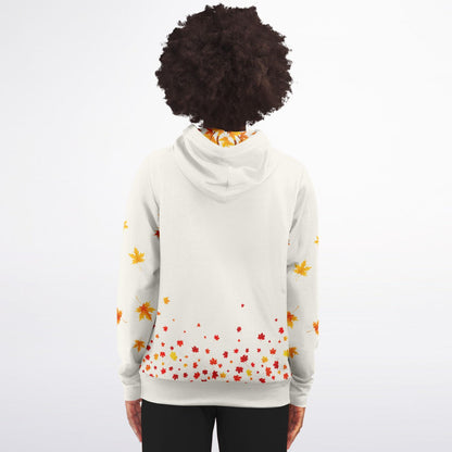 A person shown from the back wearing a white hoodie with a scattered autumn leaf print in orange, yellow, and red, paired with black pants against a plain white background.