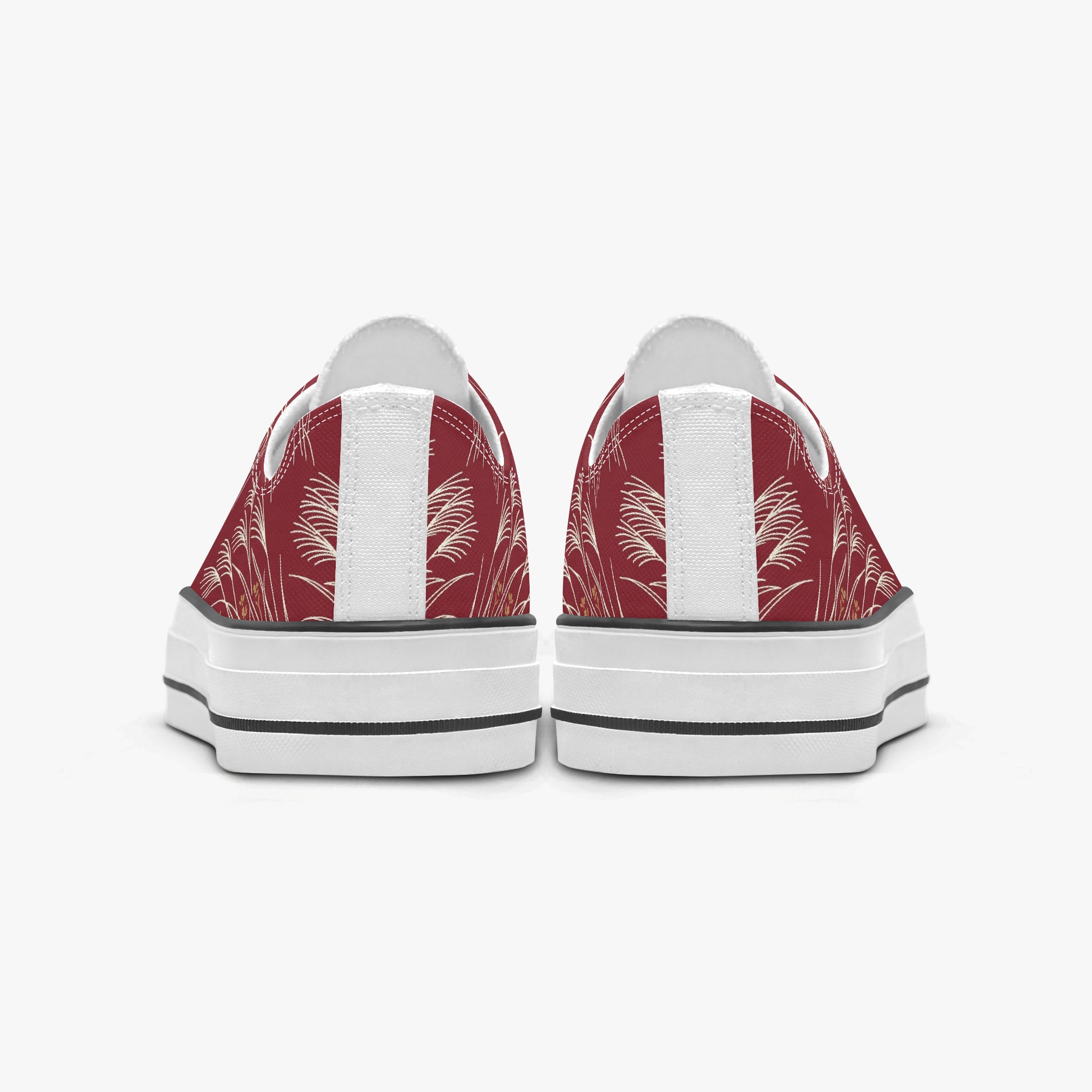 A pair of low-top canvas sneakers shown from the back, featuring a red and white palm leaf pattern on the canvas uppers, white leather side panels, and thick white platform soles with black stripes.