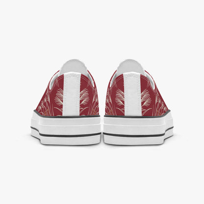 A pair of low-top canvas sneakers shown from the back, featuring a red and white palm leaf pattern on the canvas uppers, white leather side panels, and thick white platform soles with black stripes.