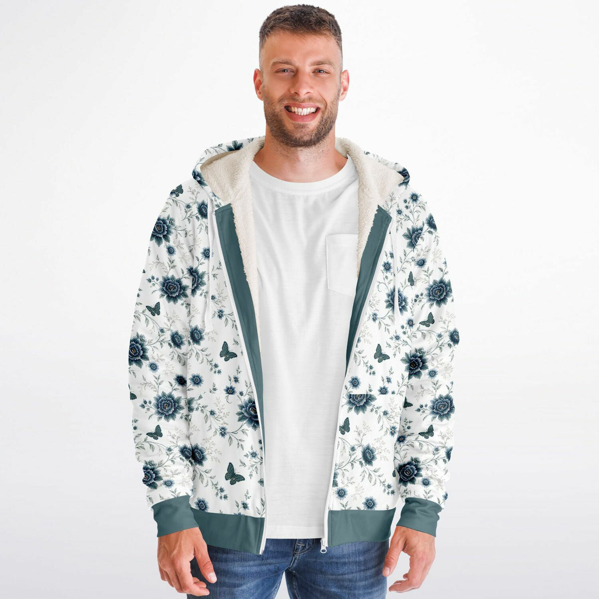 A man wearing a white zip-up hoodie with a dark blue floral and butterfly pattern, featuring a green interior lining and cuffs, layered over a white t-shirt and blue jeans against a light gray background.