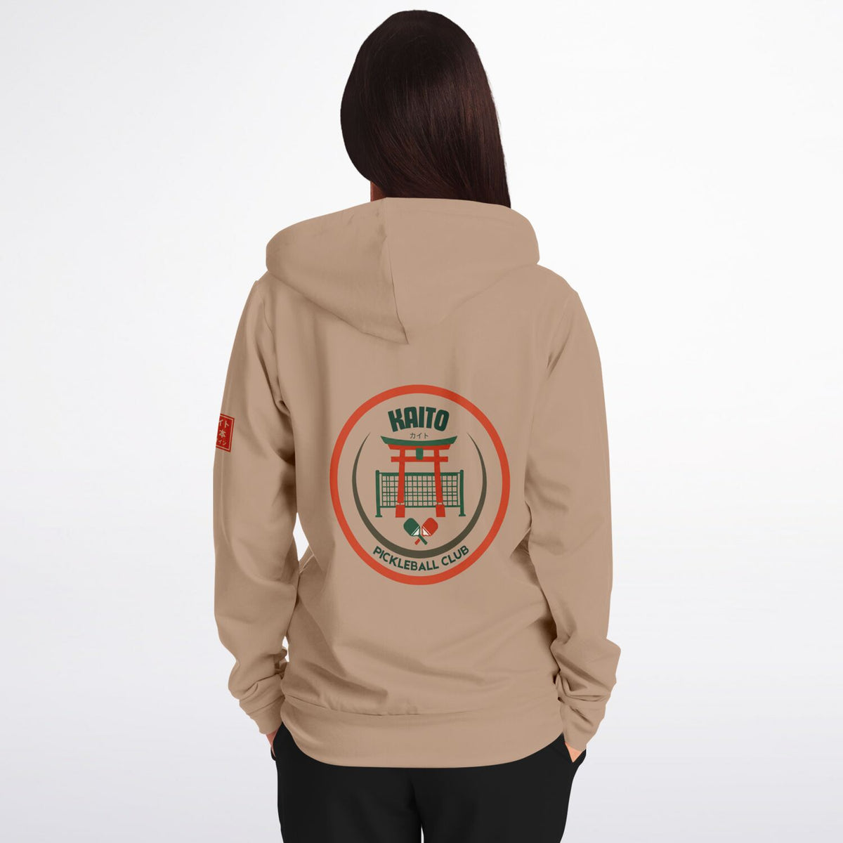 A woman viewed from the back wearing a beige hoodie with a large circular 'Haitio Pickleball Club' graphic on the back and a small red graphic on the left sleeve, set against a plain white background.