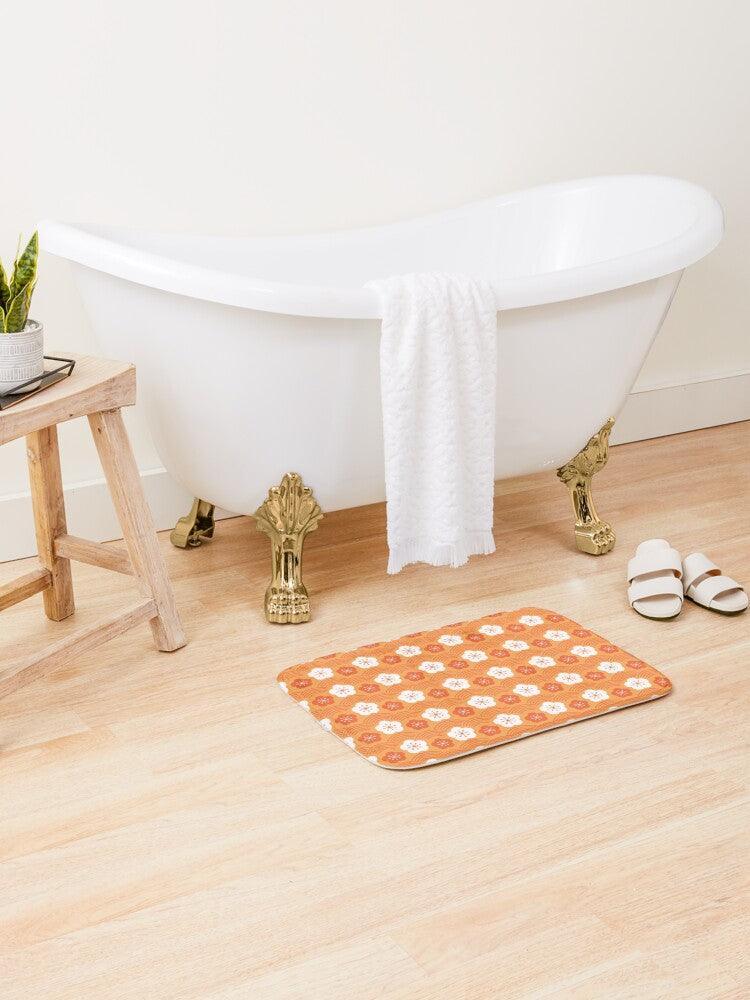 White and Dark Orange Flower Japanese Pattern Bath Mat.   Japanese style bathmats are the perfect finishing flourish for a stylish, personality-filled bathroom, and this bath mat is as practical, as it is stylish - the anti-slip backing keeps the bath mat firmly in place and reduces the risk of slipping. 100% Microfiber. Vibrant print exit in 2 sizes 34” x 21” (86 x 53 cm) or 24” x 17” (61 x 43 cm). Anti-slip backing. Binding around the edges. Machine wash cold, gentle cycle. Tumble dry low or line dry. 